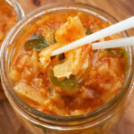 Homemade kimchi being eaten out of a jar with chopsticks.