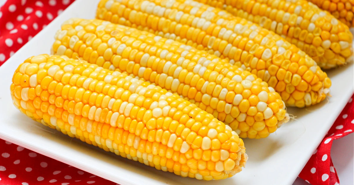 Yellow and white corn on the cob cooked in the Instant Pot on a white serving platter.