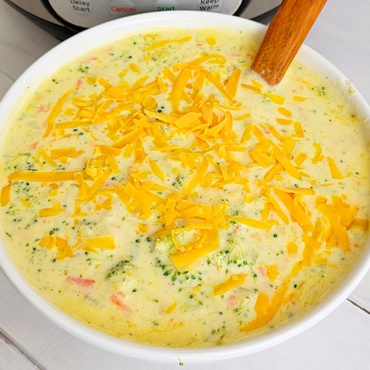 Bowl of Instant Pot Broccoli Cheese Soup with Chicken on an orange runner ready to eat