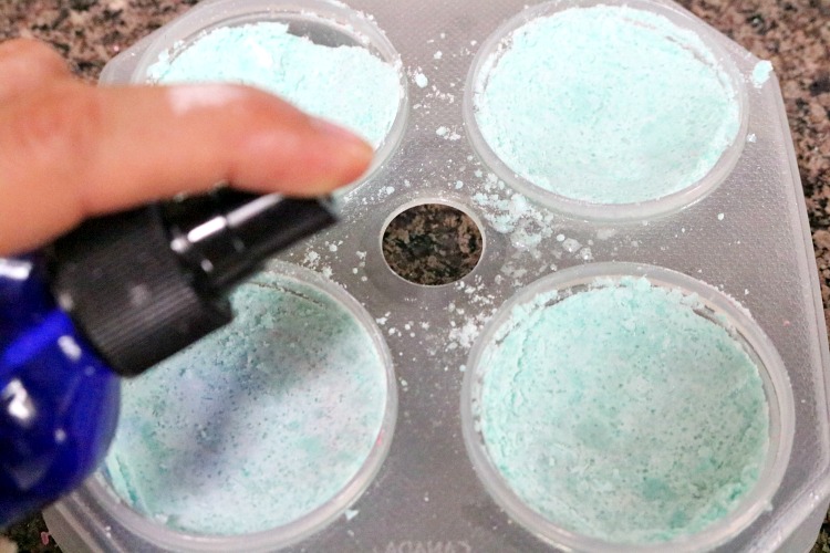 Headache bath bomb mixture in mold being sprayed lightly with water