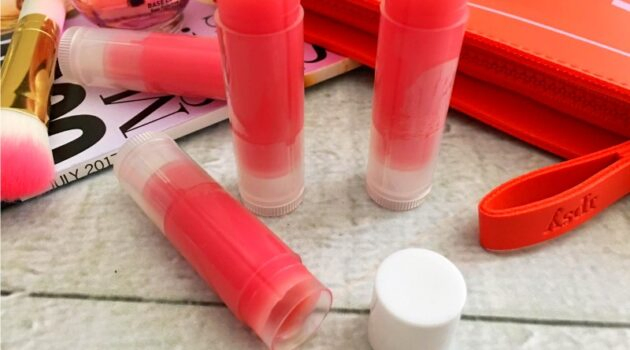 Close up of tubes of mica tinted lip balm on a white wood table