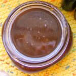 Close up of homemade brown sugar face scrub in a half pint mason jar on yellow cloth