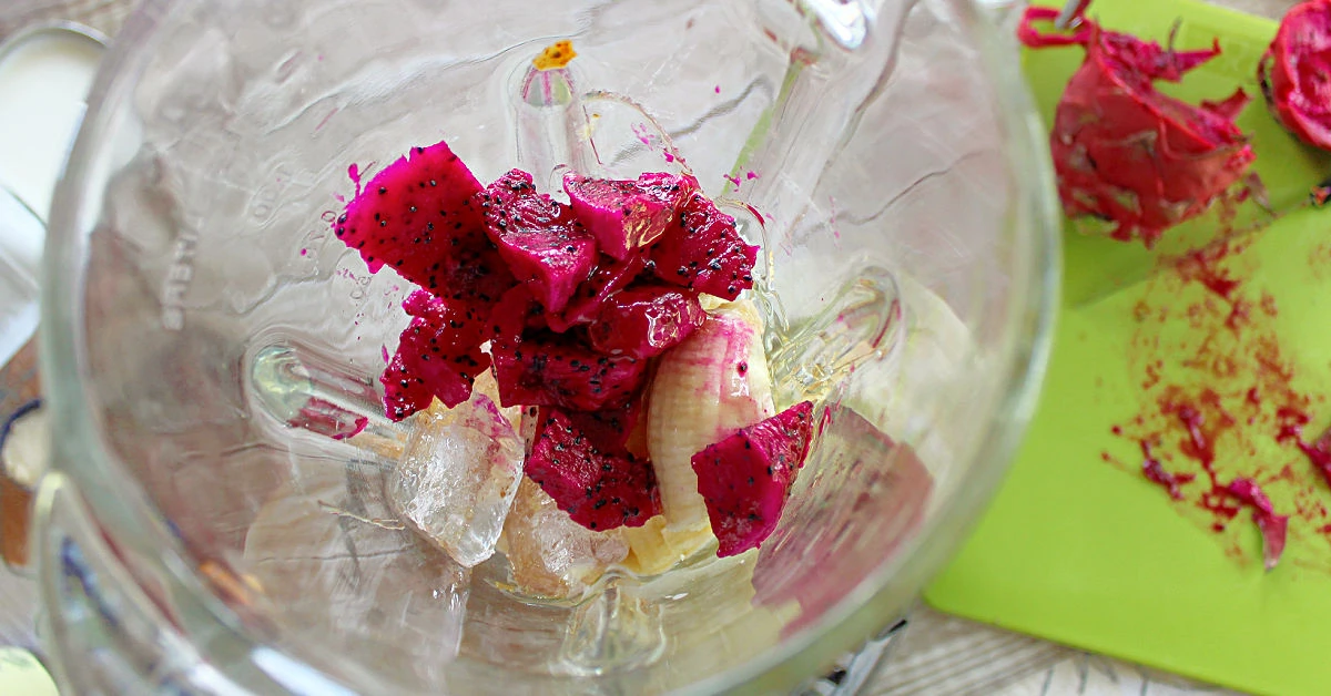 Dragon fruit, banana, honey and ice cubes in a blender.