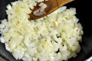 Chopped onions being sauteed with butter in a pan