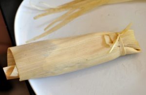 Corn husk wrapped up with tamale mixture inside