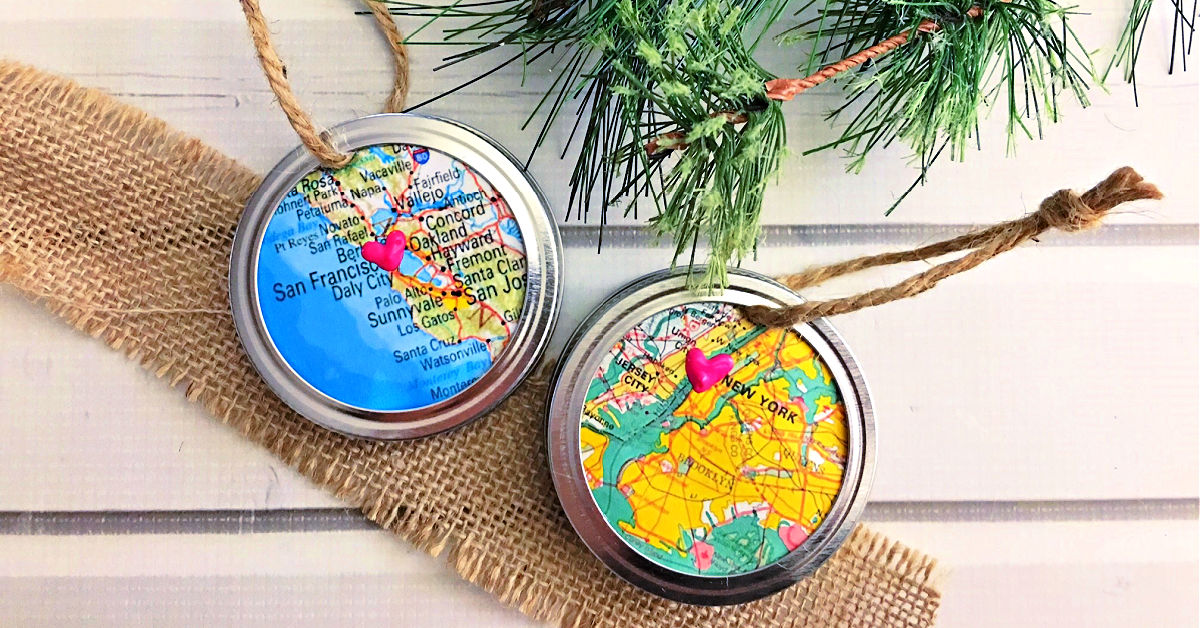 Two Mason Jar Ring Map Ornaments on a white table with Christmas tree branch.
