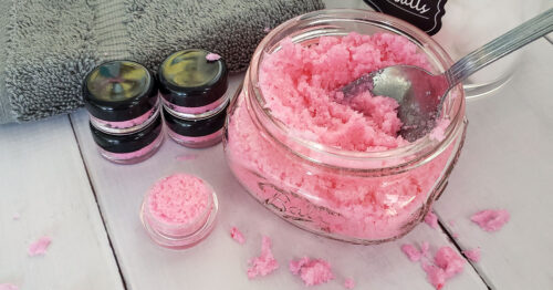 Lip scrub being scooped out of a jar with a spoon into smaller containers.