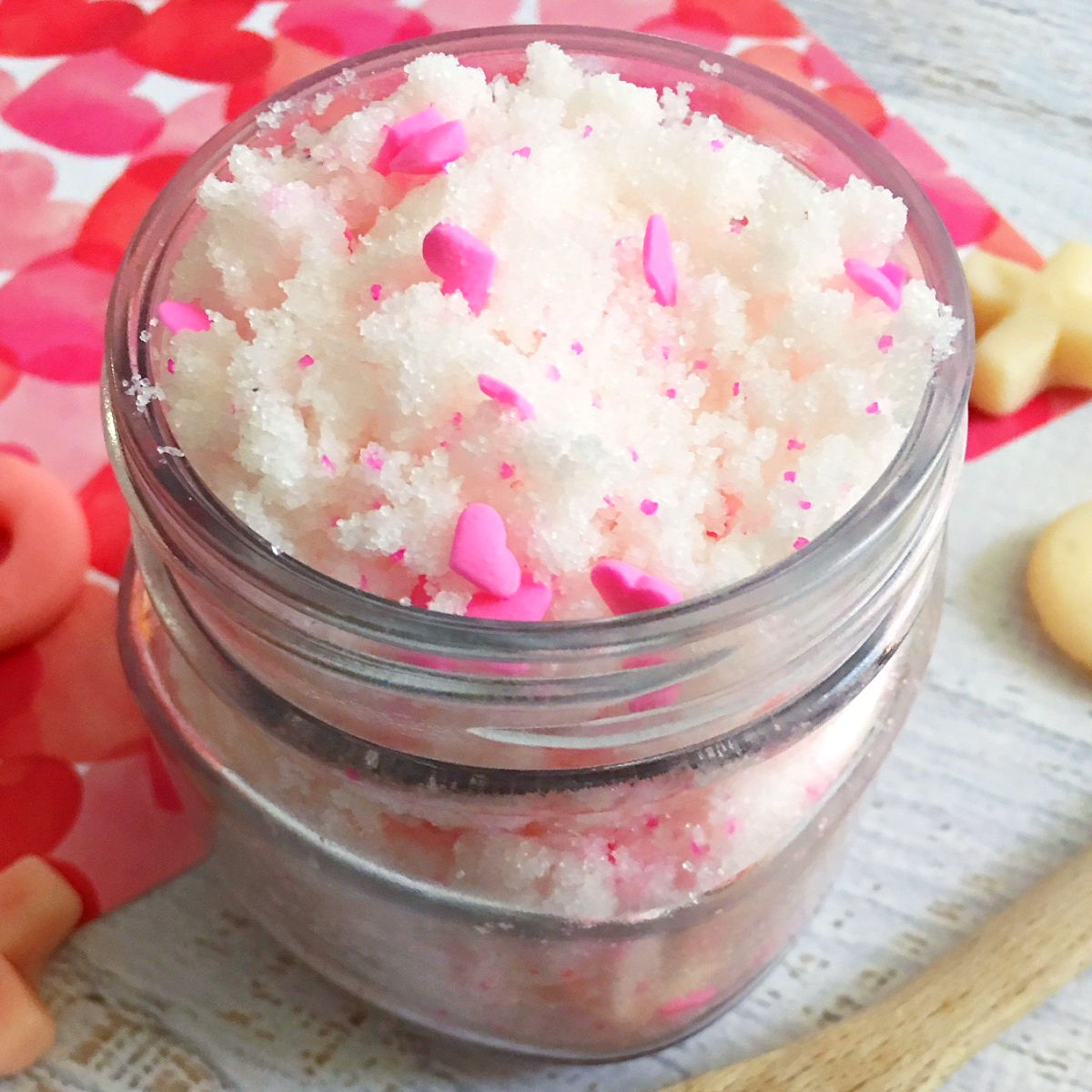 Close up with exfoliating vanilla sugar scrub with pink hearts in a glass jar for Valentine's Day