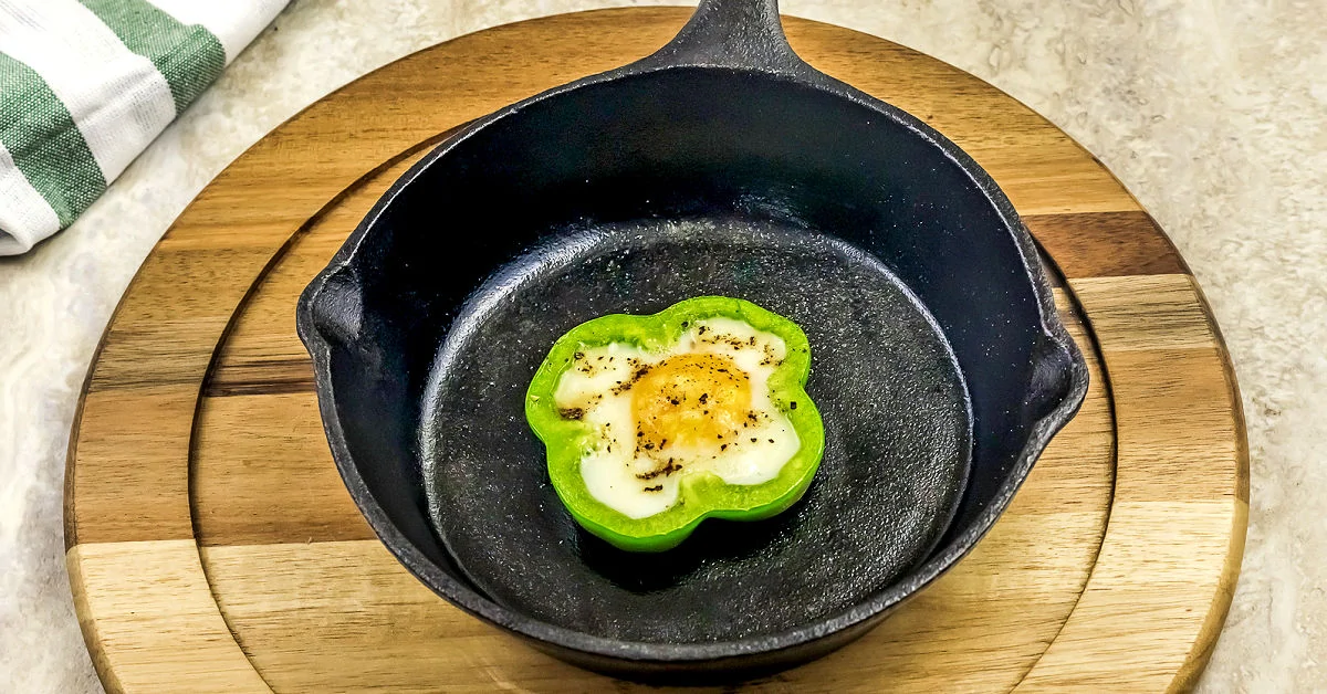 Cooked egg in a bell pepper slice in a cast iron pan.