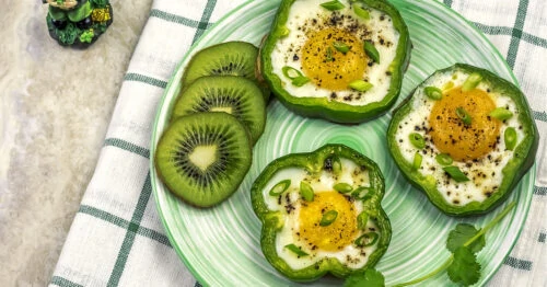 Overhead view of bell pepper eggs on a green plate.
