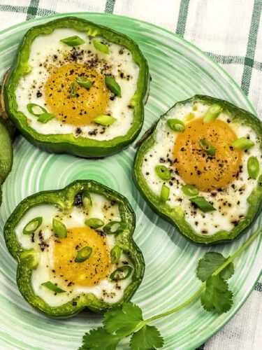 Three green bell pepper eggs on a green plate with kiwi slices.