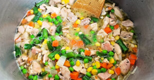 Chicken and veggies being sauteed in a sauce pan.