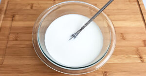 Cornstarch slurry in glass bowl with small whisk.