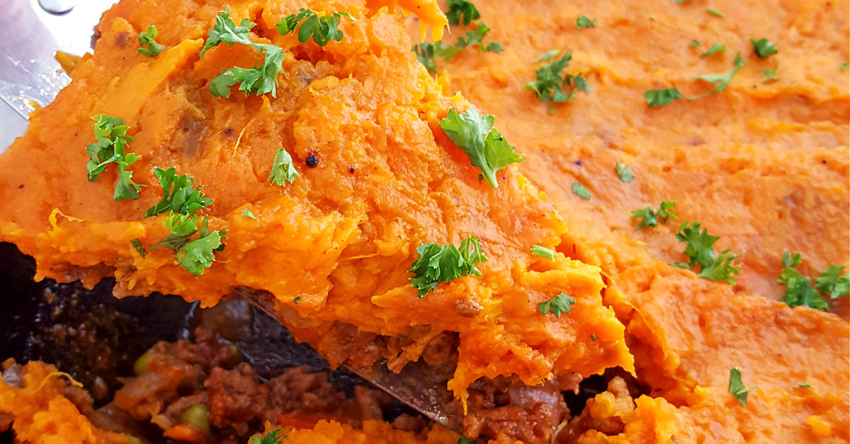 Sweet Potato Shepherd's Pie in cast iron skillet being served with spoon.