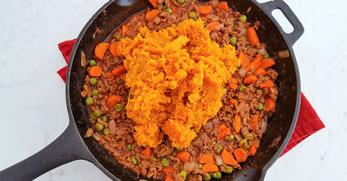 Sweet potatoes scooped into the cast iron skillet with the ground beef, carrots, onions and peas.