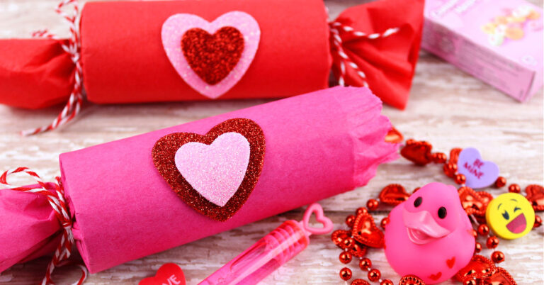 Two homemade treat poppers for Valentine's Day on a white washed wood table.