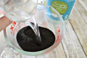 Pouring coconut oil into coffee grounds