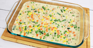 Chicken pot pie filling poured into a glass casserole dish.