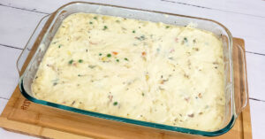 Gluten free chicken pot pie topping spread over filling in casserole dish.