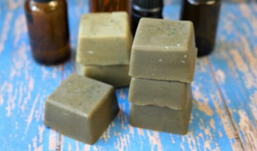 A few matcha green tea powder soap bars on weathered blue wood table with oil bottles