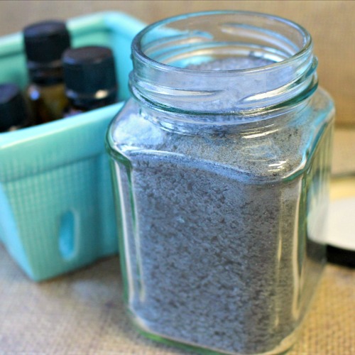 Jar of activated charcoal detox bath soak next to container of essential oils