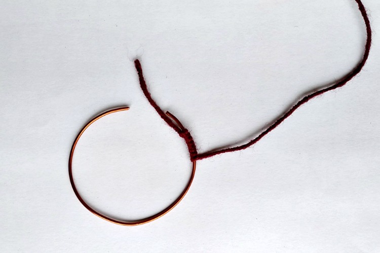 Wire hoop with brown yarn being