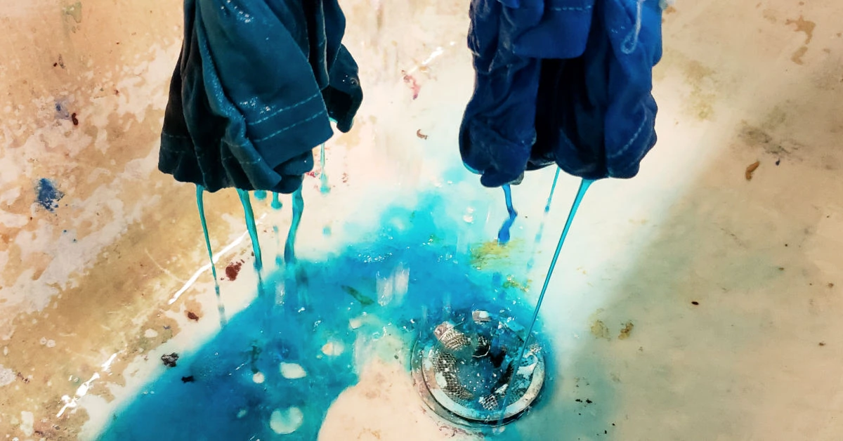 Blue dye being rinsed from tie dyed shirt in sink.