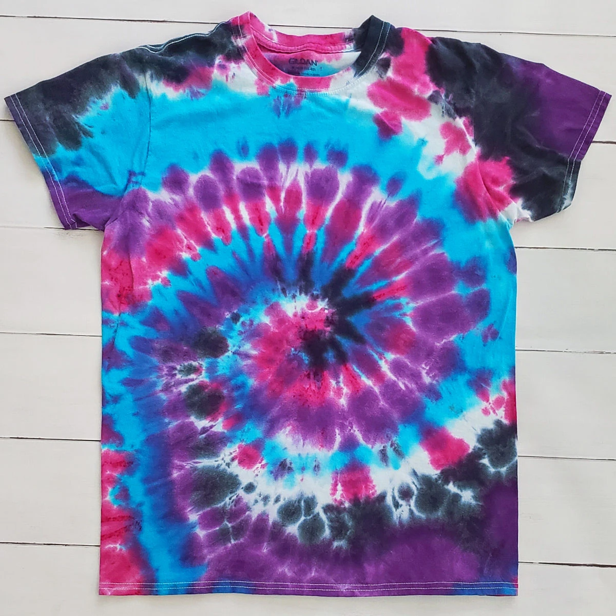 Spiral tie dye t-shirt with galaxy colors: black, purple, pink, blue and white.