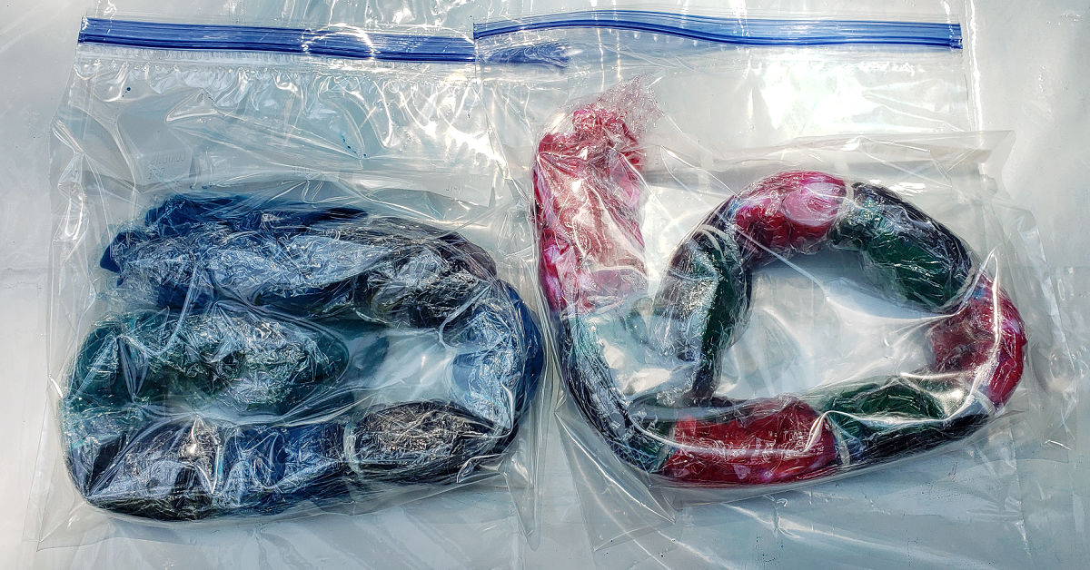 Two stripes design tie dye shirts wrapped in plastic wrap and put in a plastic bag.