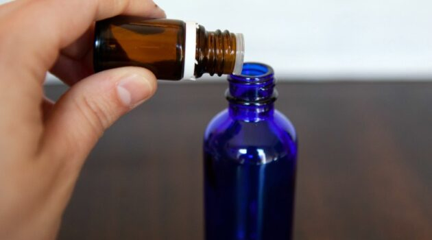 Essential oils being added to blue glass spray bottle