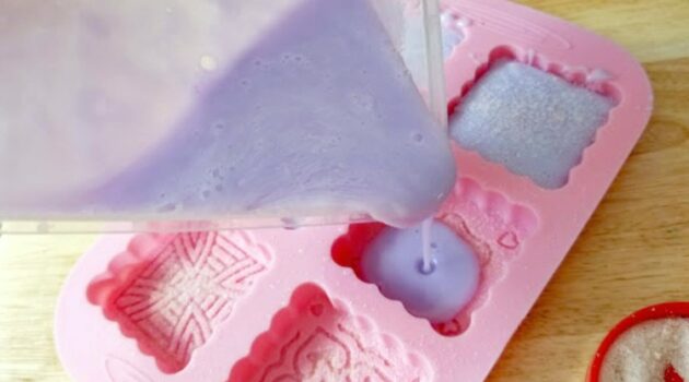 Lavender salt scrub soap mixture being poured into the pink silicone mold