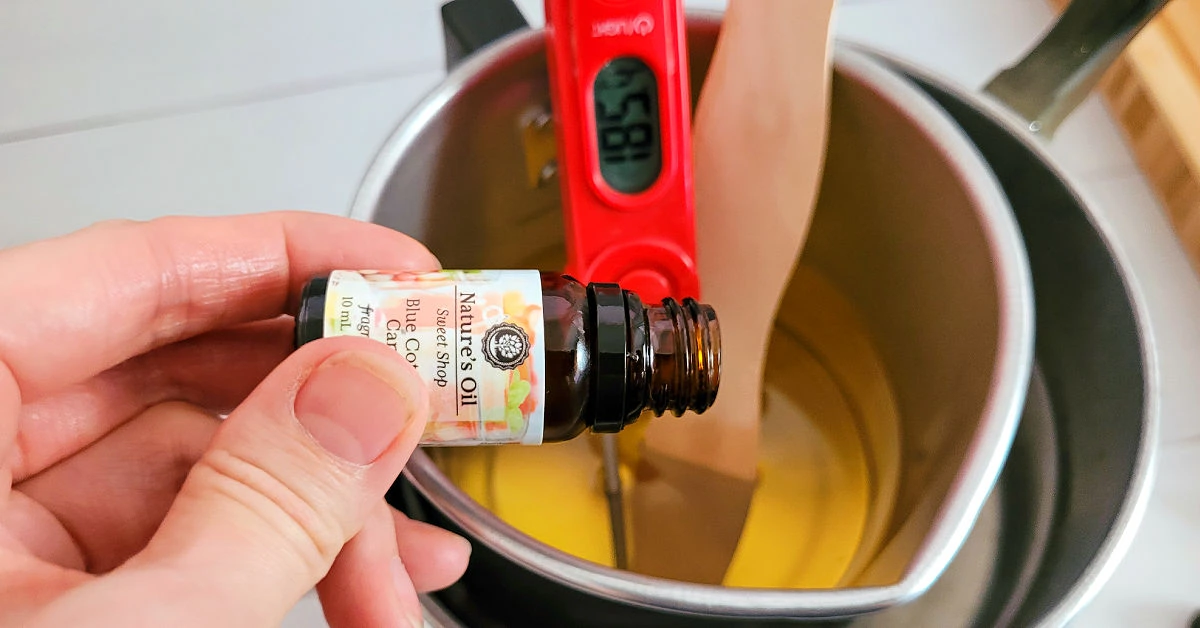 Fragrance oil being poured into melted soy wax.