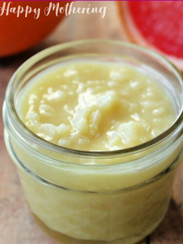 Homemade cellulite cream in a small mason jar on table with grapefruit slices.