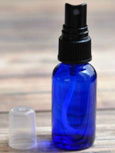 Blue spray bottle of homemade face toner on wood table