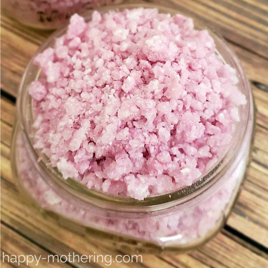 Close up shot of pink bubbling bath salts that resemble pop rocks candy in a half pint mason jar on a wood table
