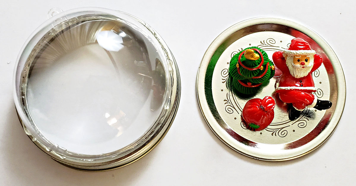Christmas figurines glued to a mason jar lid and a plastic globe glued to a mason jar ring.