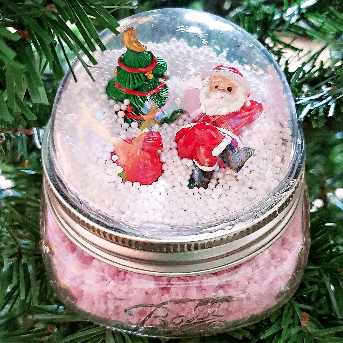 Close up of Santa Snowman Snow Globe Mason Jar Topper in Christmas tree.
