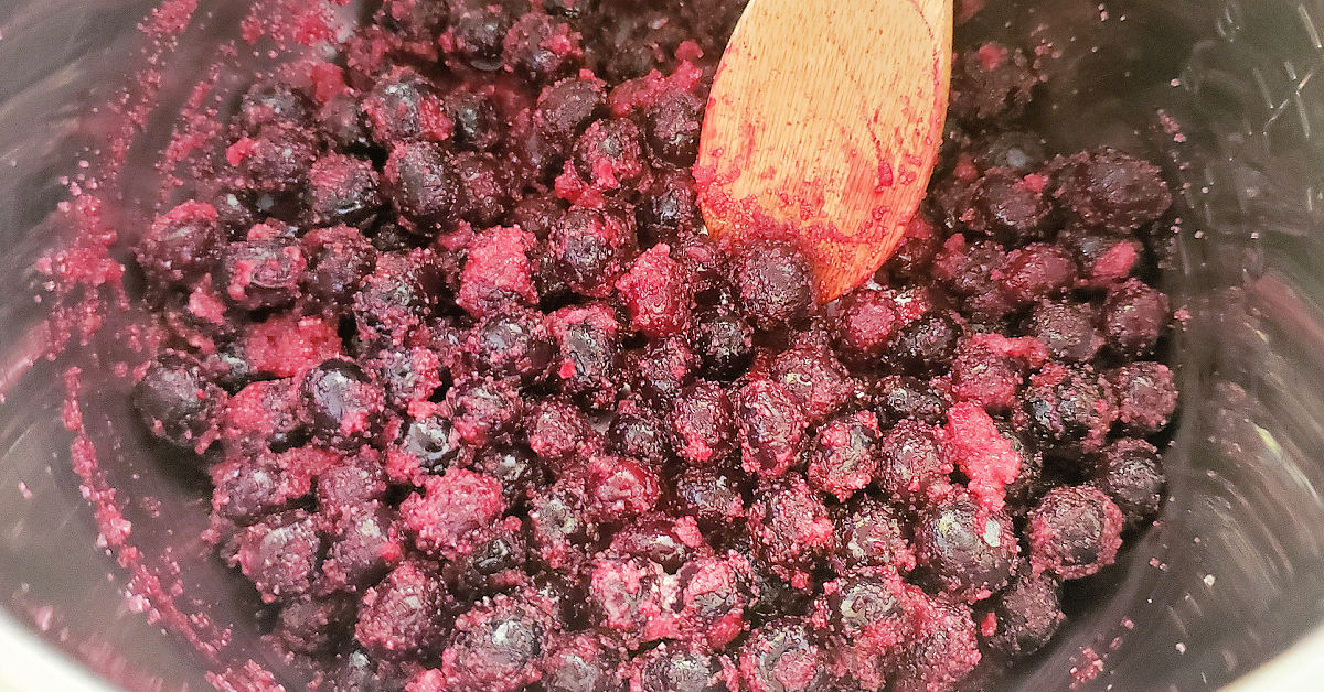 Blueberry jam ingredients being added to Instant Pot inner pan.