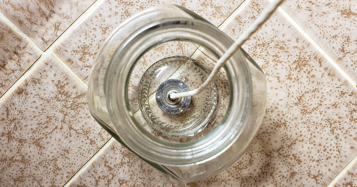 Wick glued into bottom of glass jar on a kitchen counter