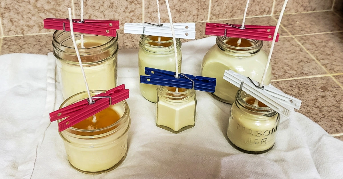 6 small glass jars with beeswax poured into them cooling into beeswax candles