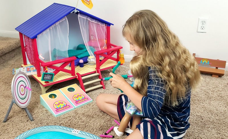 Kaylee playing the Camp American Girl Outdoor Games with her Truly Me Doll Abby while sitting next to the Camp American Girl Hanout on tan carpet