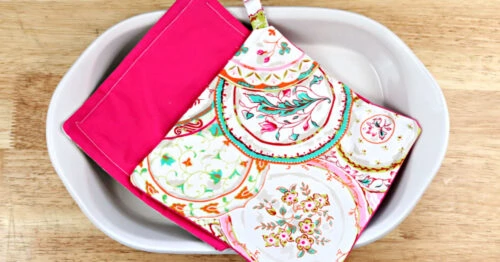 One pink and one paisley DIY pot holder in a casserole dish on a counter