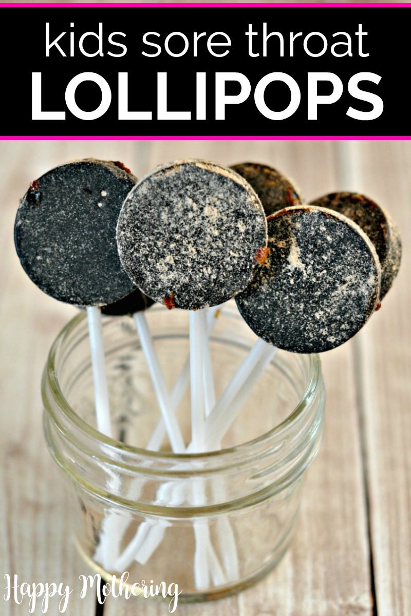 Small mason jar on wood table with 5 sore throat lollipops dark in color with white sticks