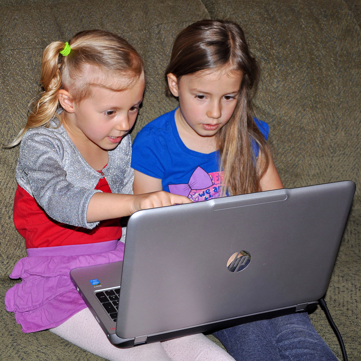 Two young girls on a laptop for homeschool lessons.