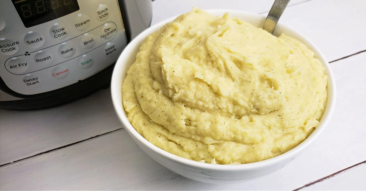 Mashed potatoes in serving bowl next to Instant Pot.