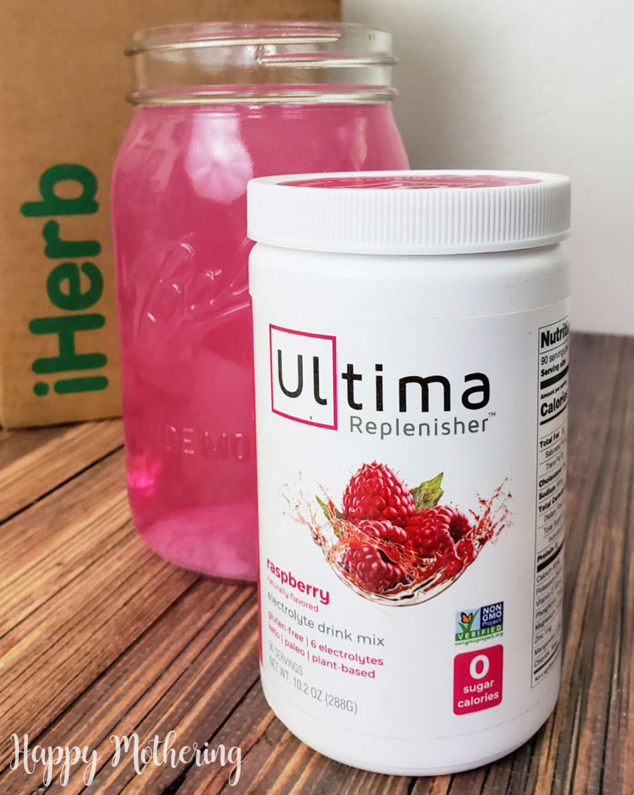 Raspberry Ultima Replenisher container in front of a mason jar of electrolyte water in front of an iHerb box.