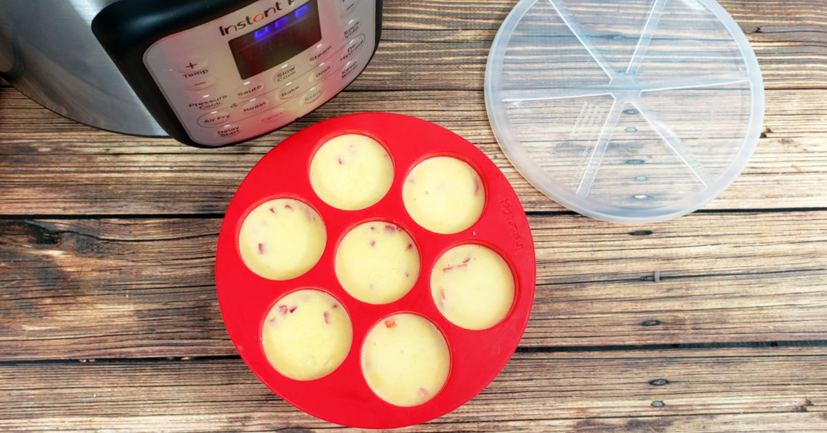 Egg bites mixture in the red silicone mold ready to be put into the Instant Pot to be cooked.