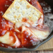 Baked brie covered in jam with cracker in cast iron pan.