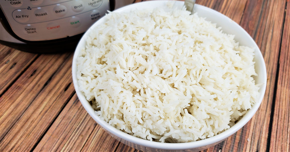 Fluffy basmati rice in white serving bowl next to Instant Pot it was cooked in.