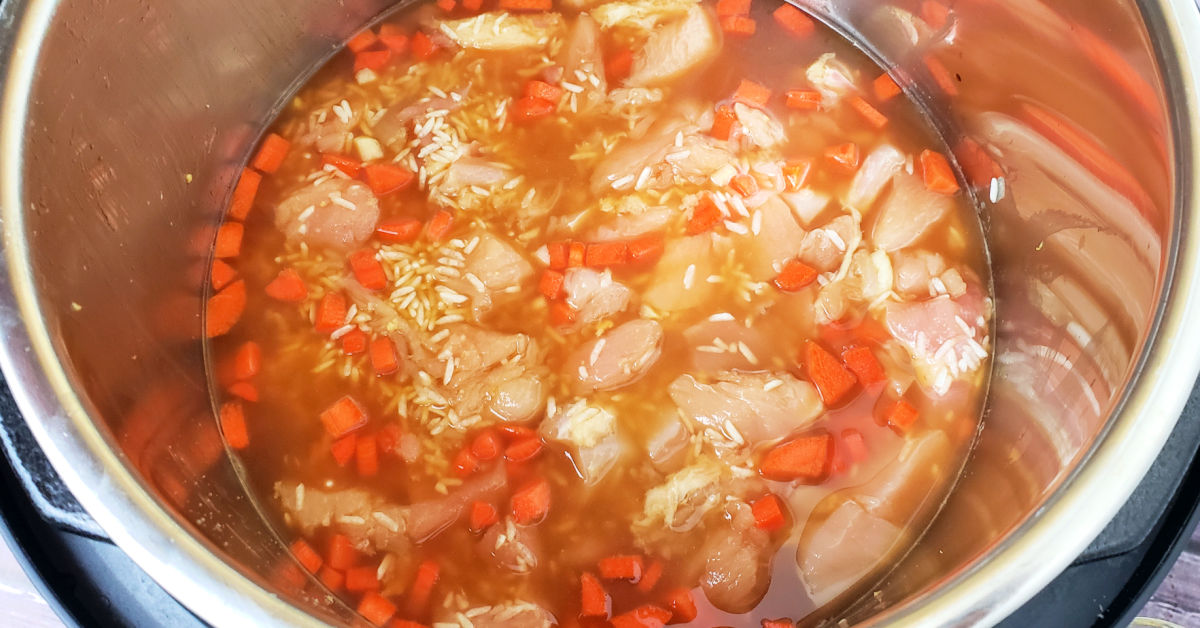Chopped chicken breast, diced carrot and chicken stock added to pot with rice and garlic.